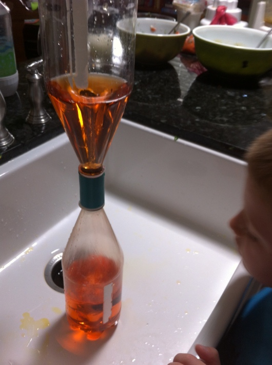 T watches the water vortex from the top to the bottom bottle.